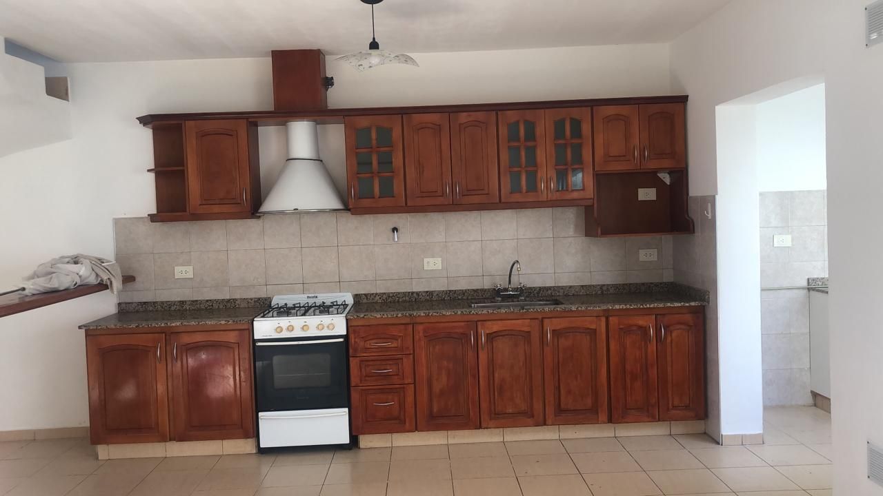 Cocina con muebles de madera, mesada de granito, cocina a gas y campana